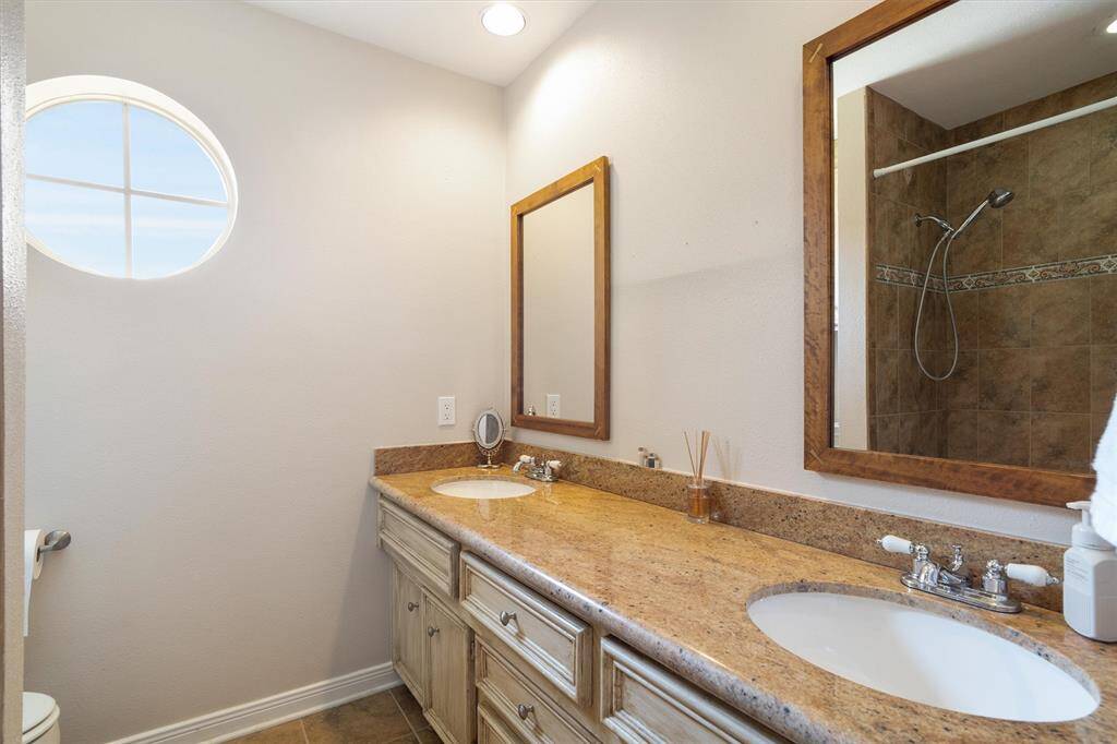 Second full bath accented with framed mirrors, double sinks, and added counter space