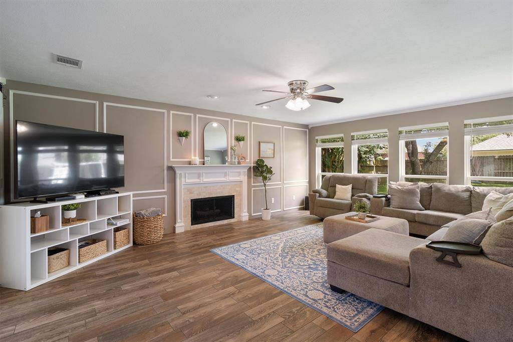 Picture perfect living room centered around a cozy fireplace, wall of windows letting in a ton of natural light overlooking your large backyard
