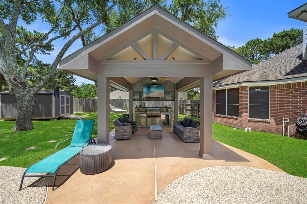 Covered Patio area with an Outdoor TV, Ceiling Fan, Light, Outdoor Seating space, and an outdoor Refrigerator!