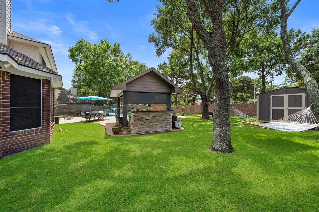 Here is a view of the backside of the Outdoor kitchen & Patio area, The New Storage Shed, and a hammock to enjoy the shaded spot.
