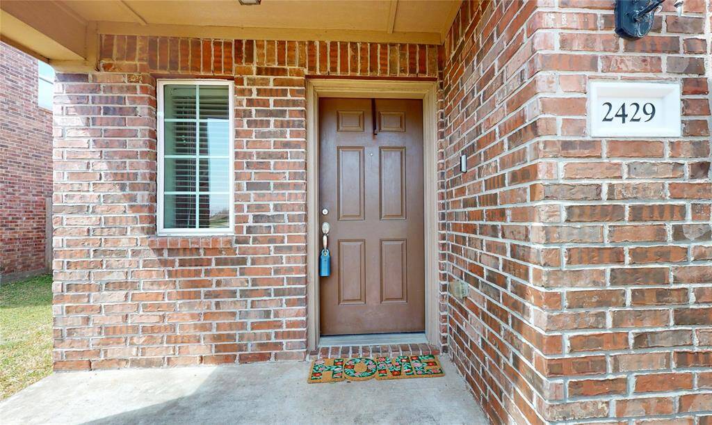 2429 Regatta Ln, Porch area at the entrance of the home, Brown wooden door and brick home.