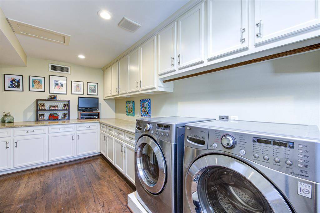 Centrally located on the second floor, the laundry room has upper and lower cabinetry, loads of work space, a wash sink and two hanging areas, one for longer hanging items and the one seen here for shorter hanging items.