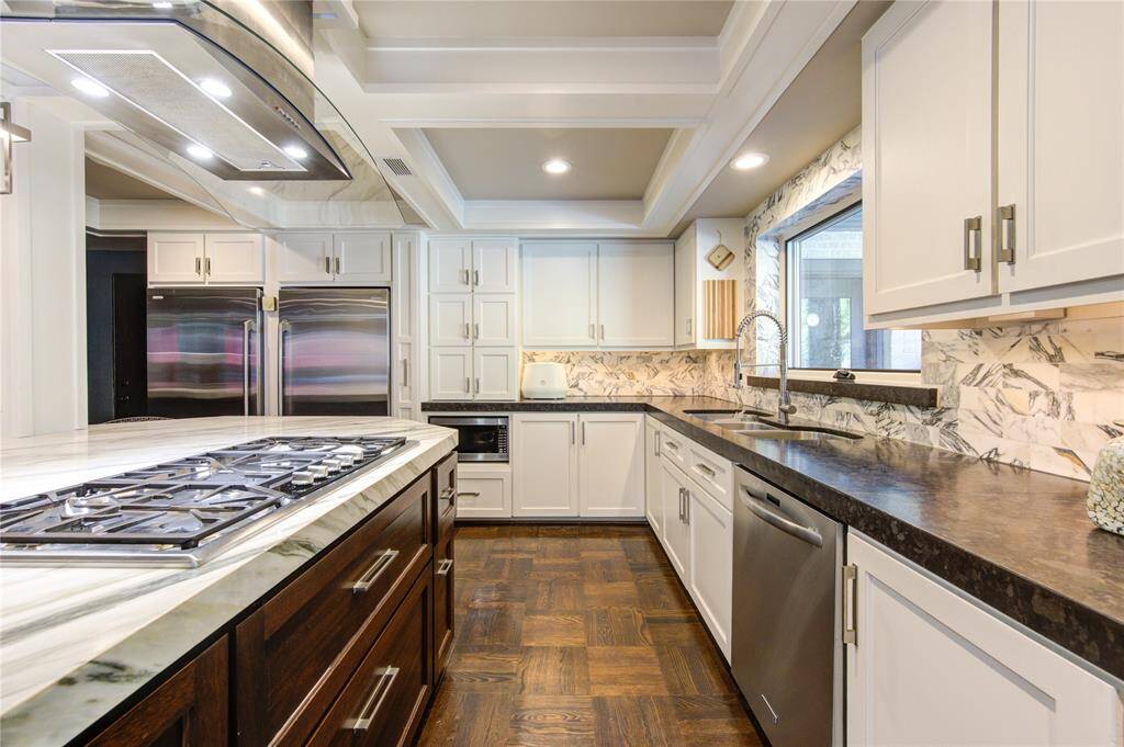 Kitchen includes side by side full sized fridge and freezer, built-in microwave with small appliance garage above, marble subway title backsplash and countertop.