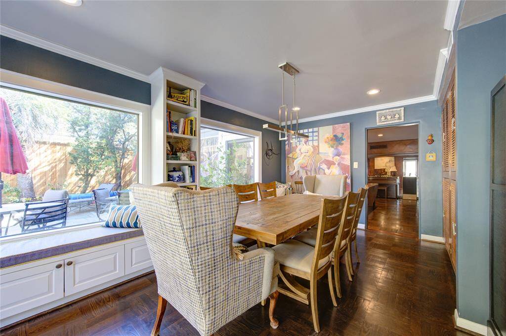 Dual picture windows set the scene for breakfast or casual meals in this renovated informal dining room.  Updates include banquette seating with built-in storage along with cookbook shelving, recessed and decorative lighting and hardwood floors.