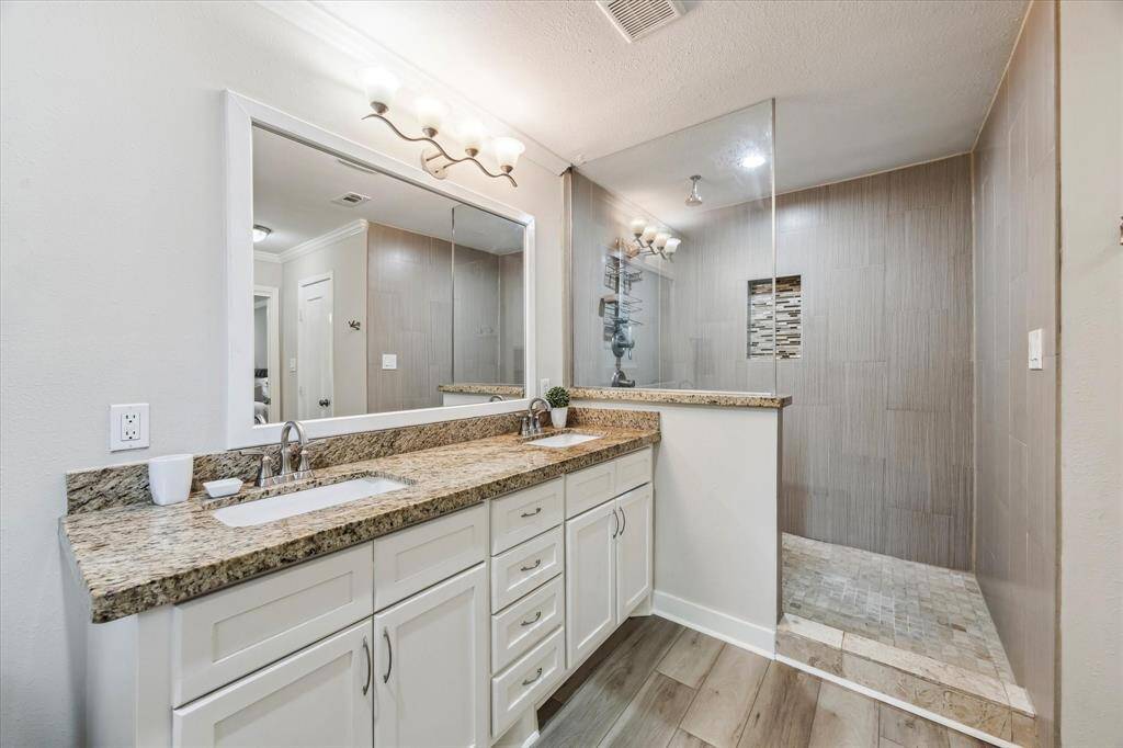 Experience luxury in the primary en-suite bathroom featuring a walk-in shower, granite countertops, and dual sinks.