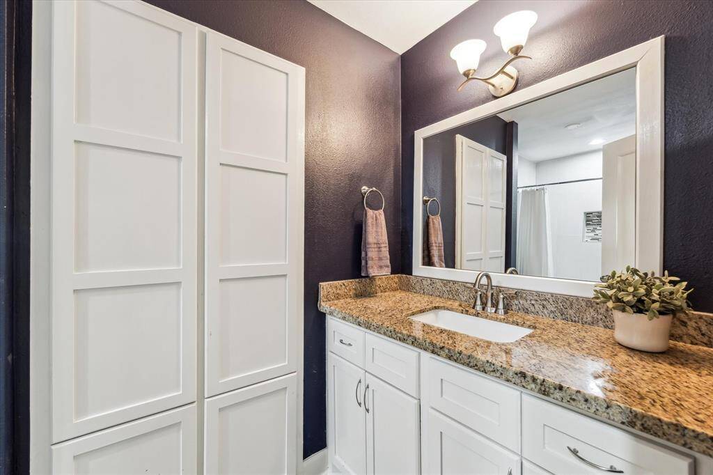 Chic secondary bathroom featuring elegant granite countertops and a sleek undermount sink.