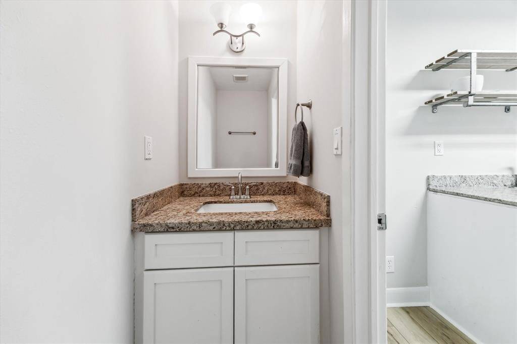 Convenient half bath with elegant granite countertops adjacent to the laundry room.