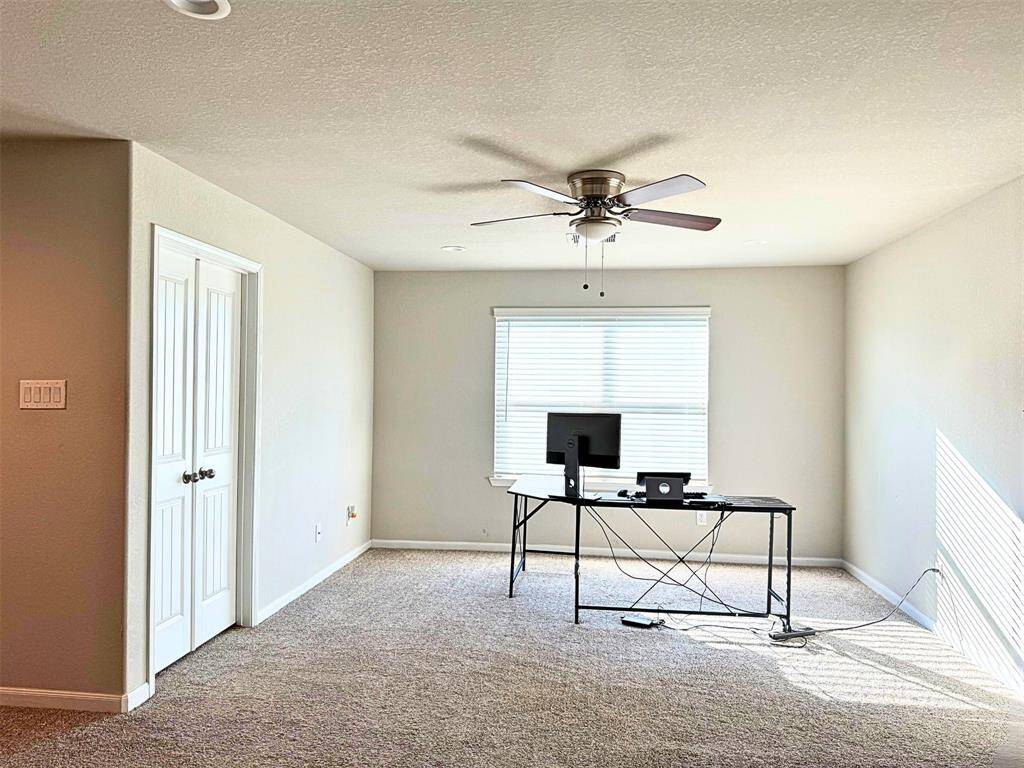 Game room with ceiling fan, ample natural light from a large window, and a stylish black stairway with a railing
