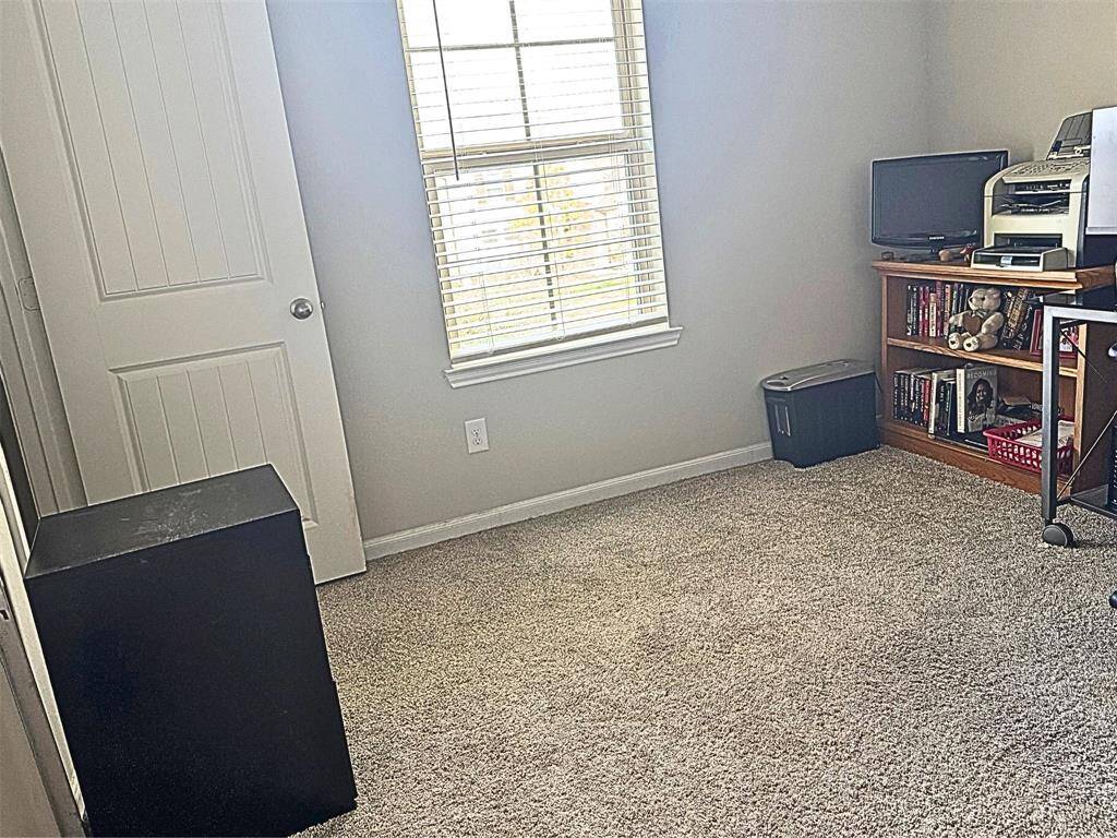Bedroom used as a office features neutral walls, a ceiling fan, and carpeted flooring. It has a window providing natural light.