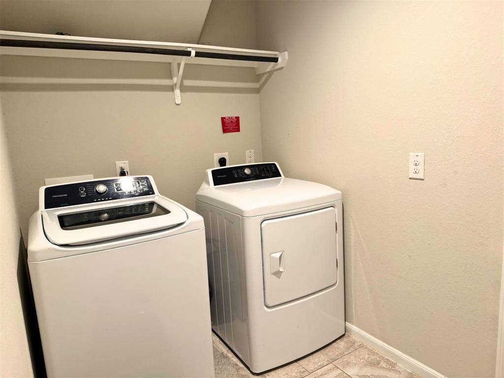 Laundry room features a shelf for storage above it. The room has tiled flooring and neutral walls.