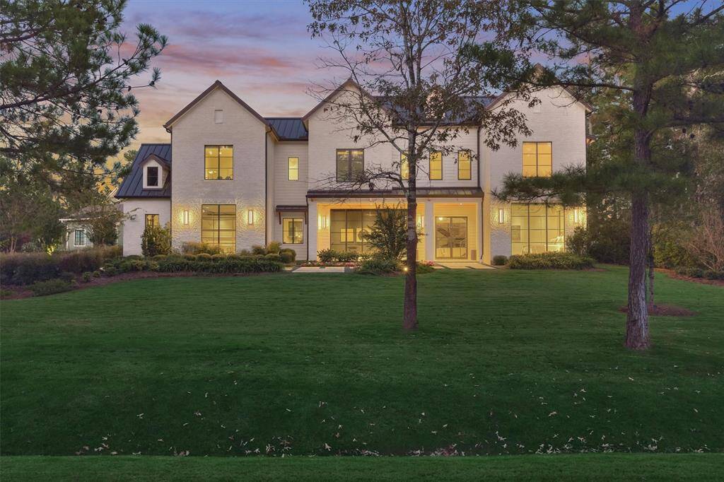 Welcome home to this custom estate in Bluejack National. A striking twilight view showcases the home’s architectural elegance, inviting warm lighting, and beautifully manicured landscaping.