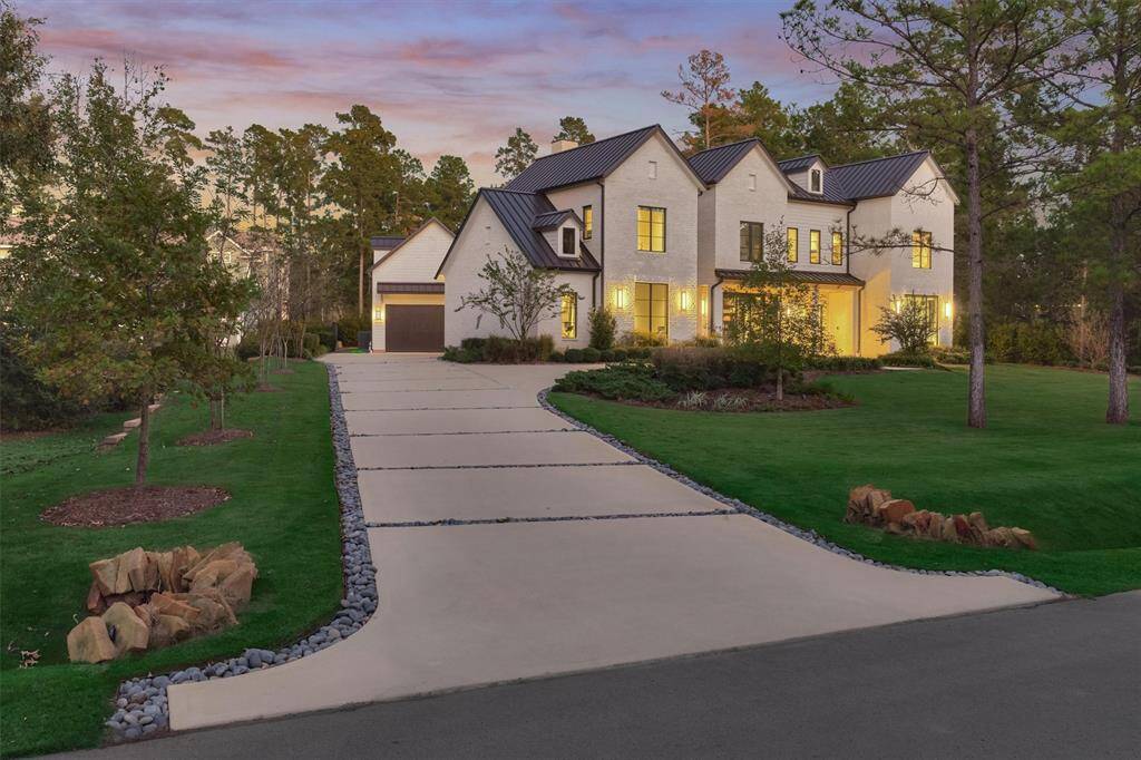Inviting approach with wide, well-lit driveway and modern landscape design leading to the motor court
