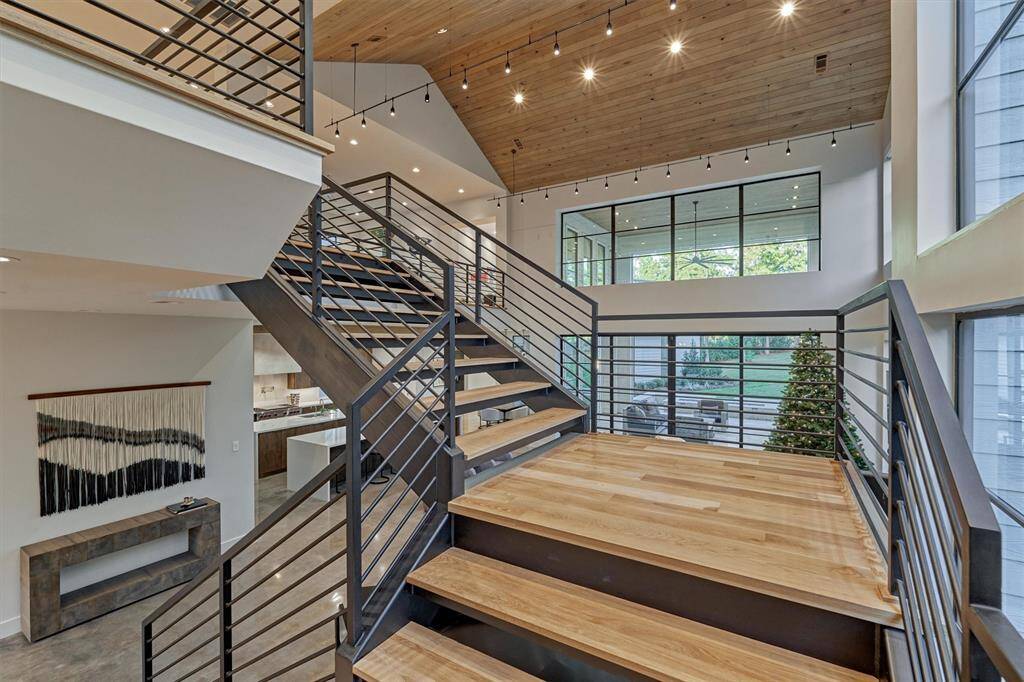 Mid-level landing gives a peek at the grand wood ceiling and curated lighting of the living room below