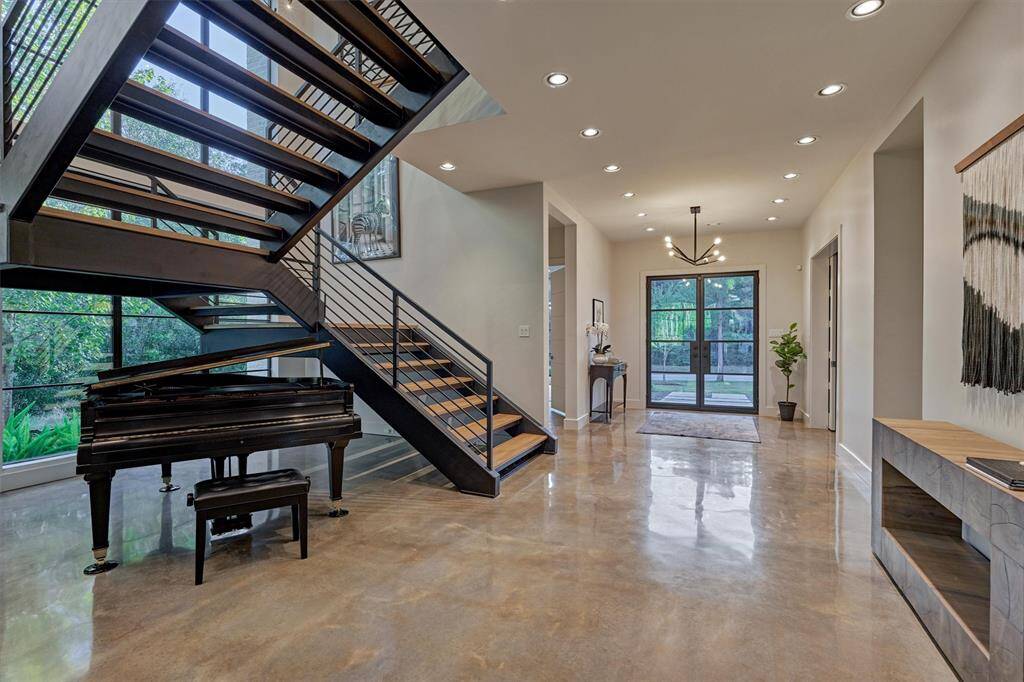 Open and airy foyer featuring sleek modern staircase, designer lighting, and space for a grand piano