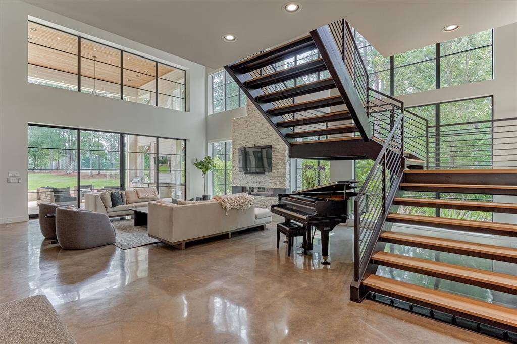 Showcases the seamless connection between foyer, floating staircase, and vaulted great room with Alder wood ceiling