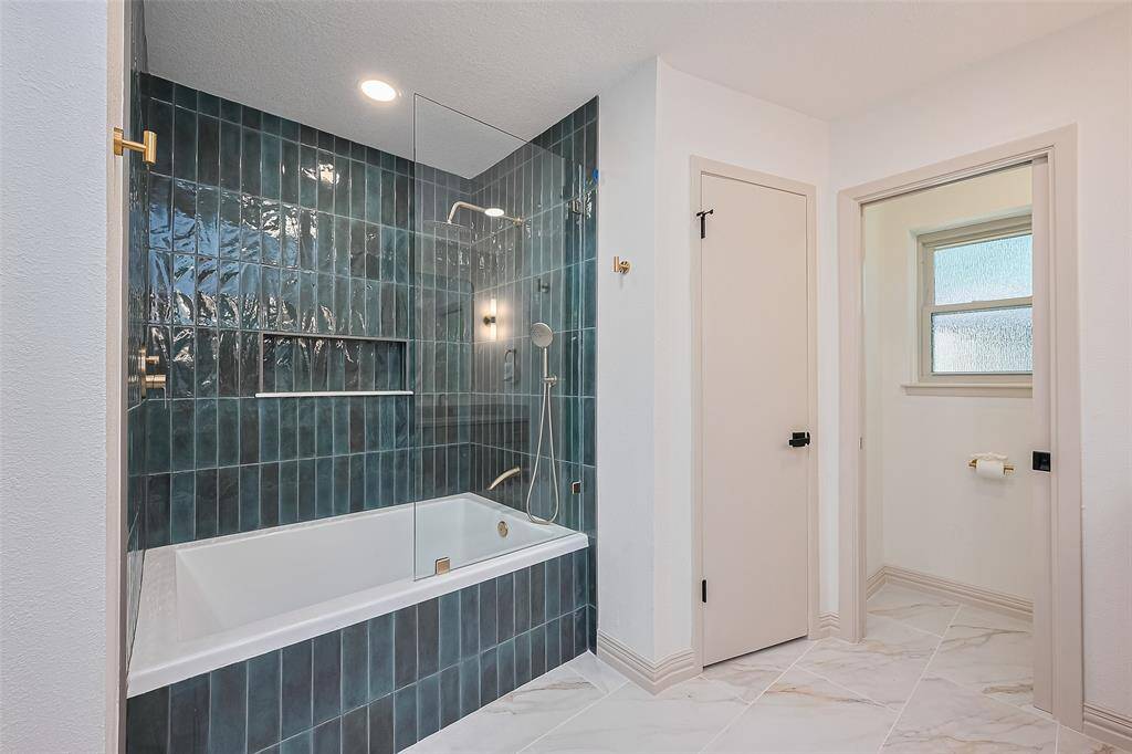 Enjoy a bubble bath in this gorgeous, tiled bath/shower combo. This bathroom's fixtures and design are top notch. Separate toilet, pocket door and window.