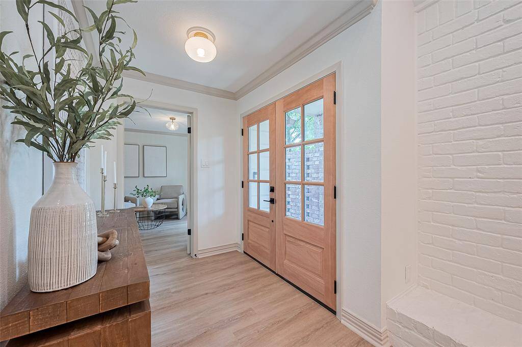 This welcoming entryway features brand new double glass doors that let in natural light. A cozy living room is visible through a doorway, adding to the home's inviting atmosphere.