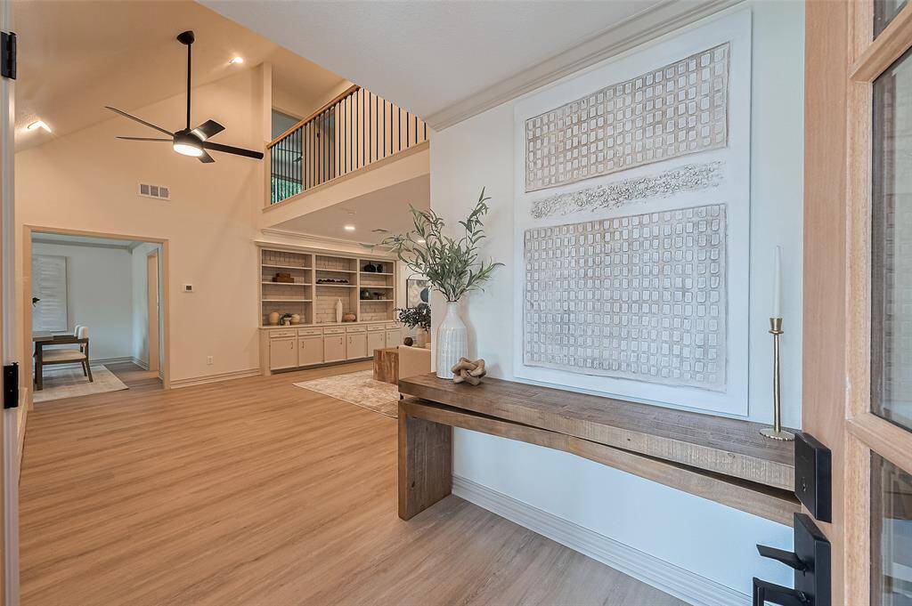 This welcoming entryway features brand new double glass doors that let in natural light. A cozy living room is visible through a doorway, adding to the home's inviting atmosphere.