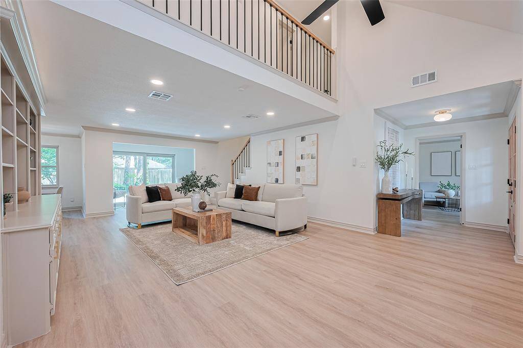 Living room is spacious and bright living area with high ceilings and modern design. It features an open layout, beautiful flooring, and a stylish staircase with an upper-level railing. Large windows provide natural light, and there's a cozy extra seating area perfect for relaxation or home office.