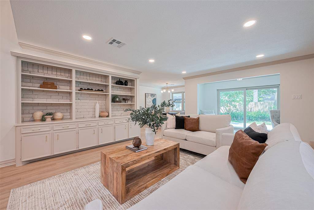 Perfectly remodeled home. Open living area features a fresh design with gorgeous modern colors, flooring, built-in shelving, and a cozy seating arrangement. It's well-lit with natural light from large windows, offering a view of the outdoors. The open layout provides easy access to the dining area, kitchen, breakfast, and outdoors.