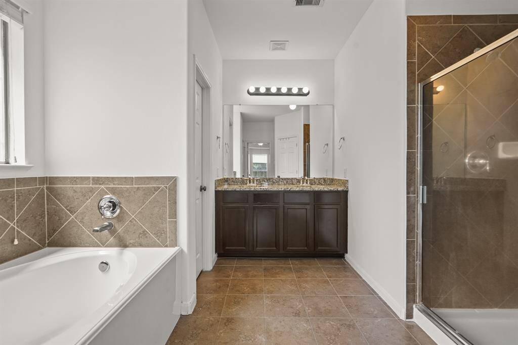 Step into comfort in this spacious primary bathroom! large a spacious walk-in shower, a serene garden tub, and a vanity area with granite countertops and dual sinks. Natural light completes the warm and inviting feel!