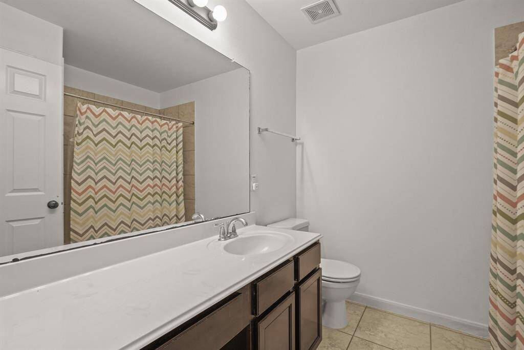 This full bathroom is located off the hall of the secondary bedrooms making it easy to share and get ready. It features am oversized vanity, wood cabinets, sleek countertops, and a large combination tub and shower.