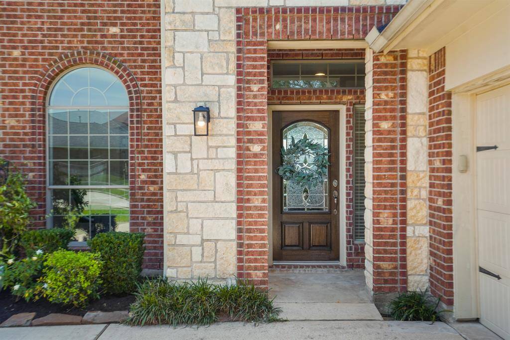 Approaching the front door you will see the beautiful brick and stone elevation, lovely landscaping, covered front porch, outdoor lantern, and stained front door!