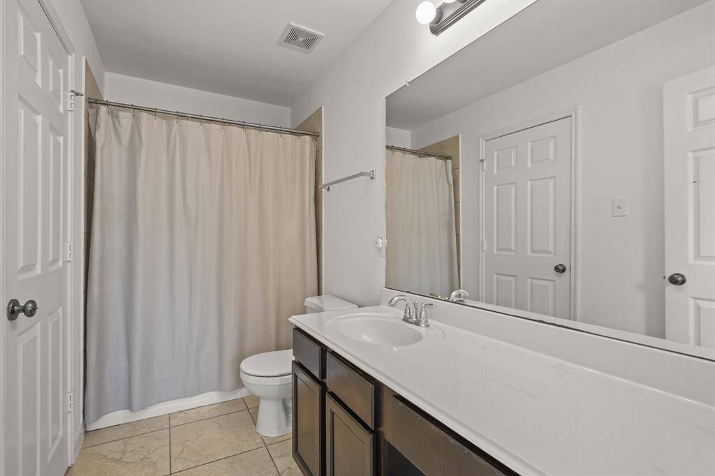 This full bathroom is located off the hall of the secondary bedrooms making it easy to share and get ready. It features am oversized vanity, wood cabinets, sleek countertops, and a large combination tub and shower.