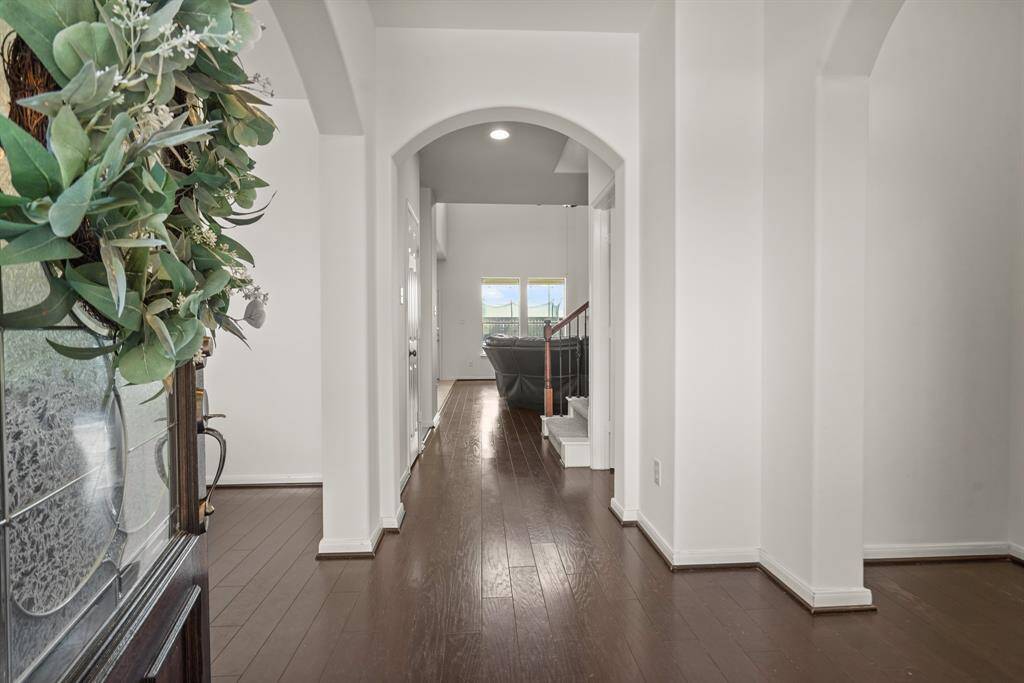 The entry way is bright, open, and features beautiful wood flooring! This welcoming corridor greets you with high ceilings, natural light, and fresh paint.