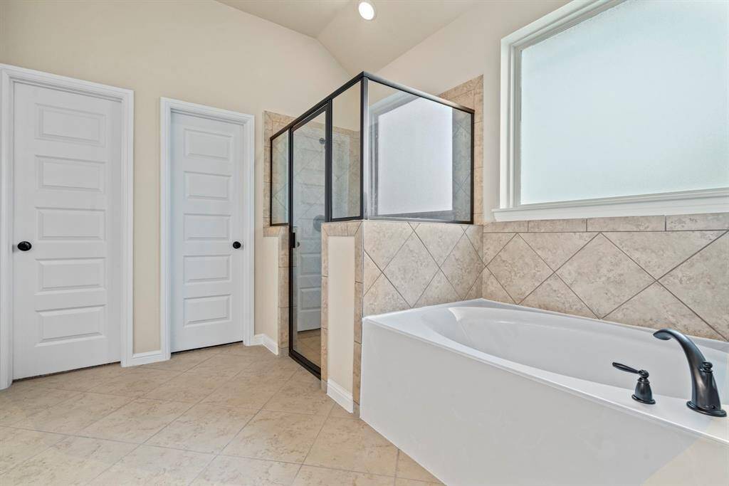Luxurious primary bathroom featuring a sleek glass shower and a relaxing soaking tub.