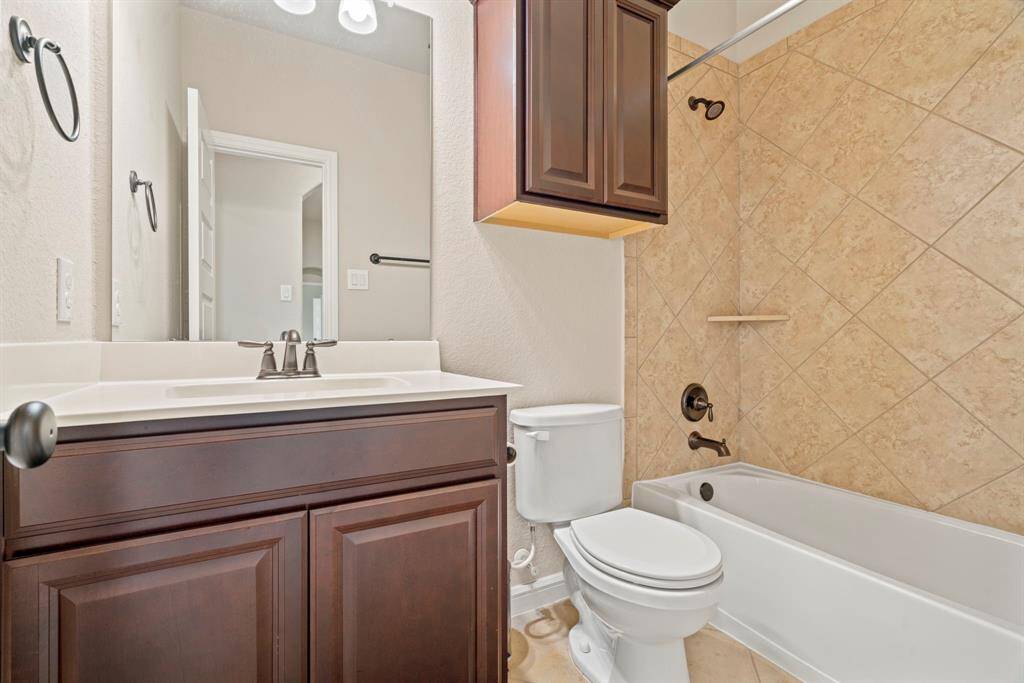Inviting hallway bathroom featuring elegant tilework and ample cabinetry.