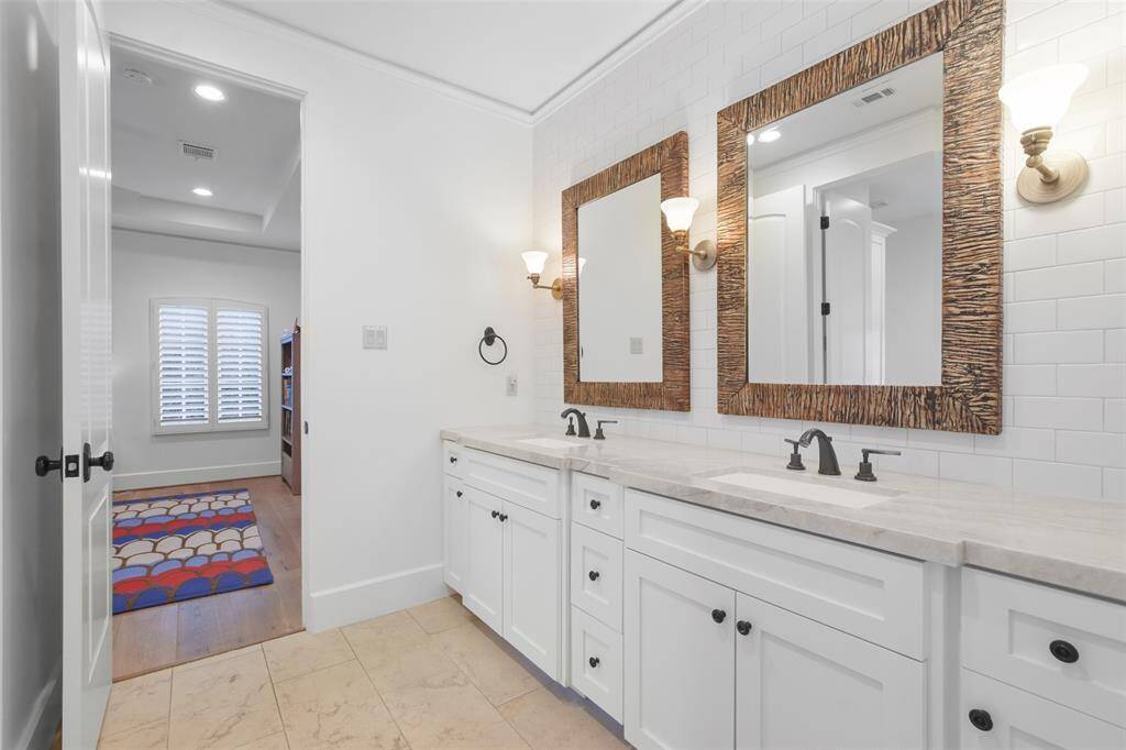 Secondary bathroom features double sinks, framed mirrors and marble countertop.