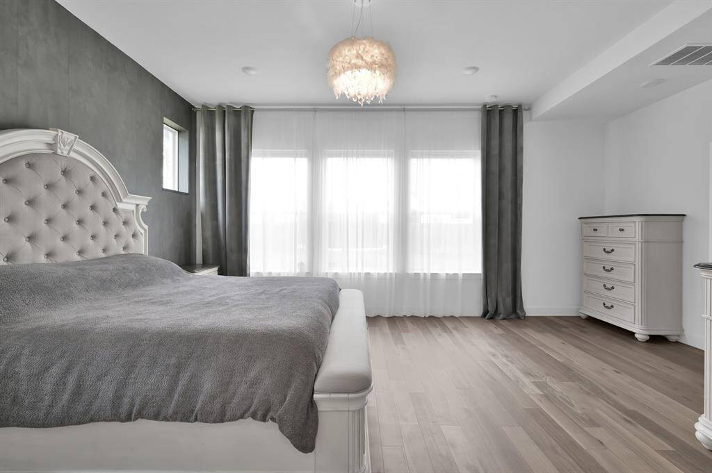 The primary bedroom features a striking wall of windows that fills the space with natural light. Expansive in size, it easily accommodates large furniture, a private sitting area, or even workout or sports equipment -offering both comfort and versatility.