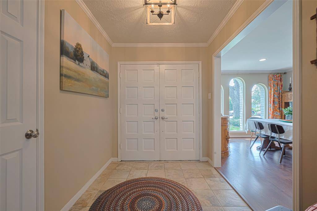 Warm foyer to greet guests with modern light fixture and crown molding all warm tones