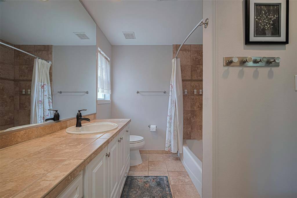 Primary ensuite bath features terracotta color tile countertop and fully tiled tub and shower combination