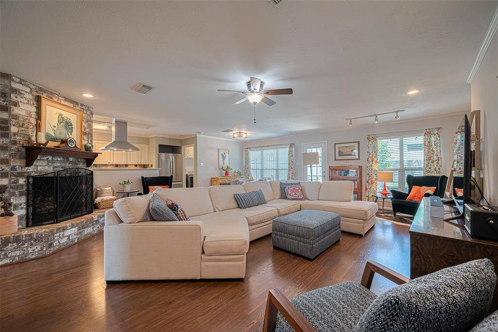 Gleaming wood laminate flooring with open living area, featuring a brick gas log fireplace and loads of windows for natural light