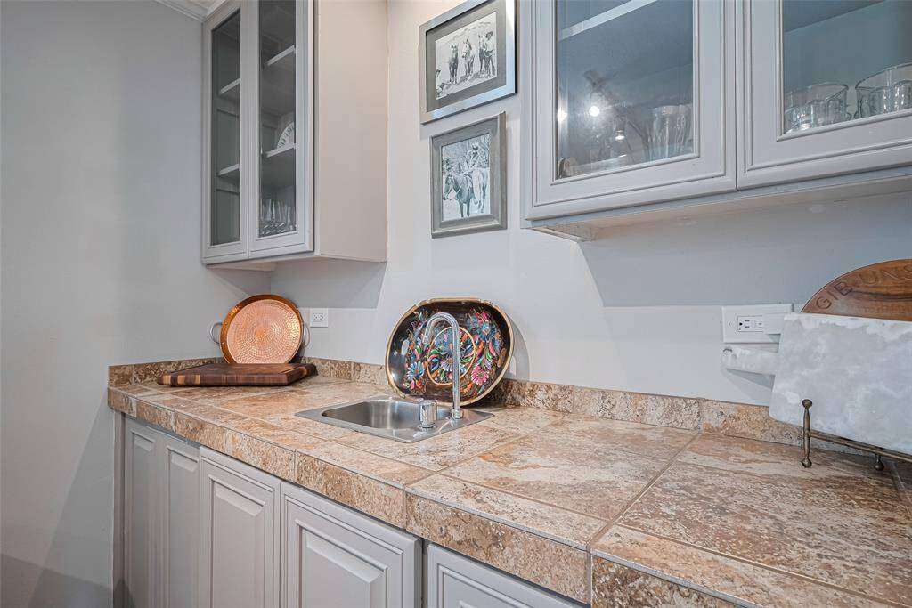 Wet bar is perfect for entertaining with feature glass shelving and storage cabinetry