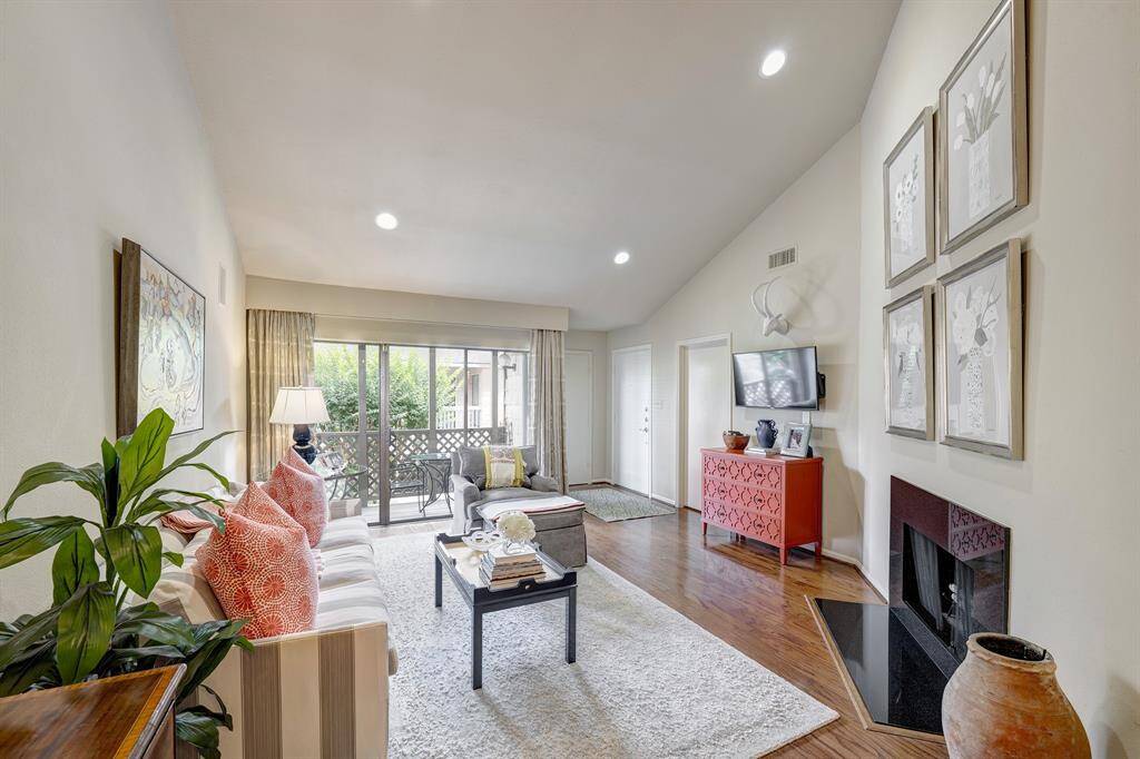 Spacious living room features a wood burning fireplace, hardwood floors, and has access to a private, covered balcony.