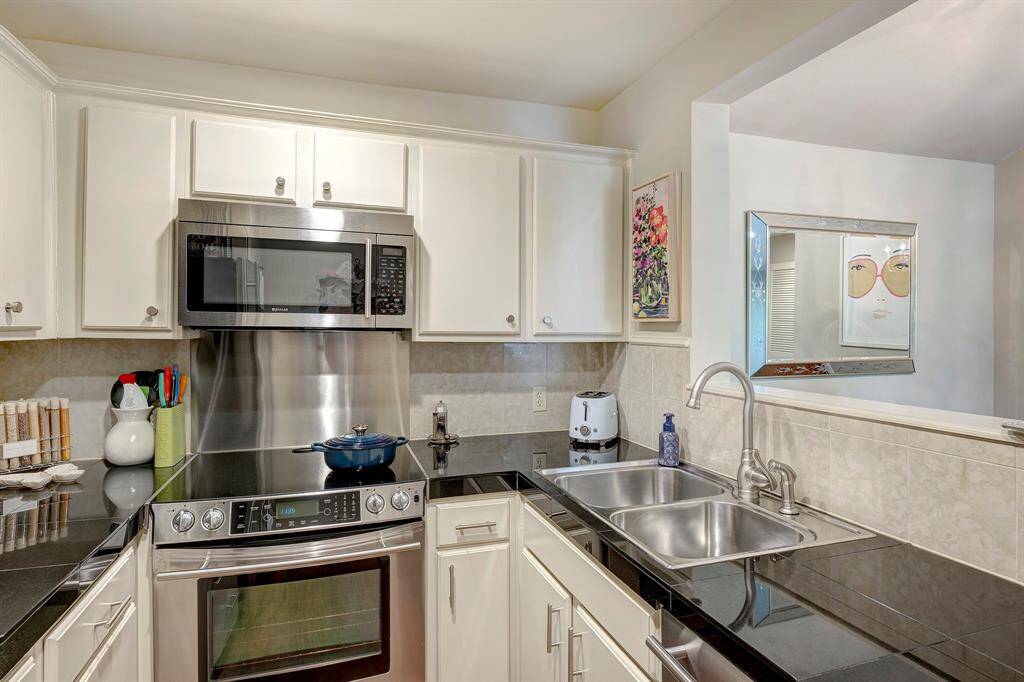 Updated kitchen with stainless steel appliances, granite countertops, plentiful cabinetry, and a convenient pass-through to the dining room.