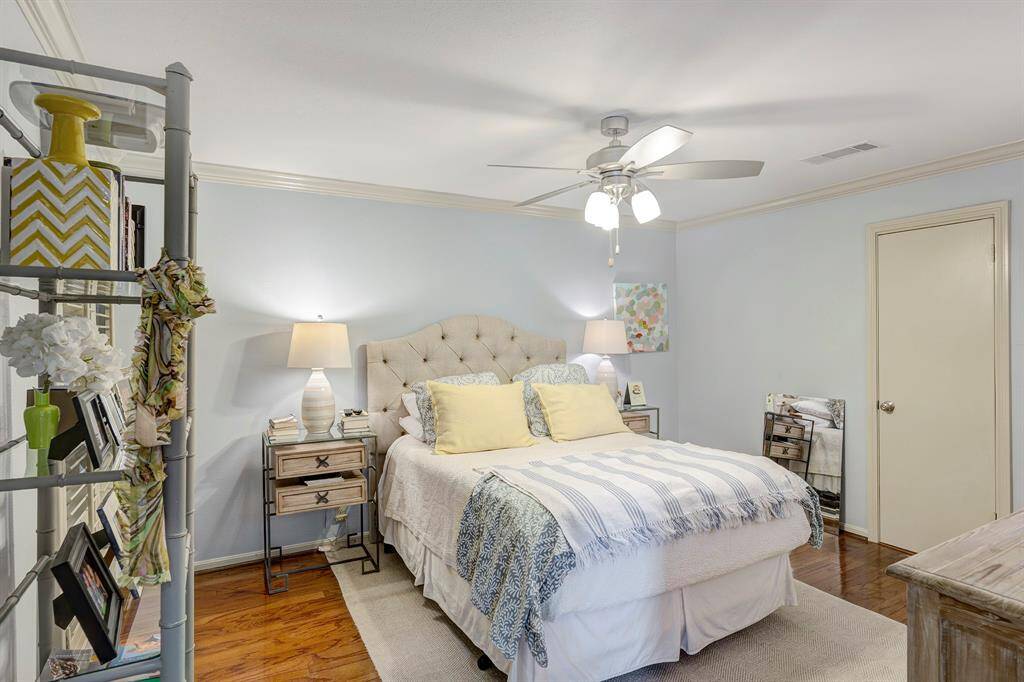 Well-sized primary bedroom featuring elegant crown molding, classic plantation shutters, and a ceiling fan for comfort.