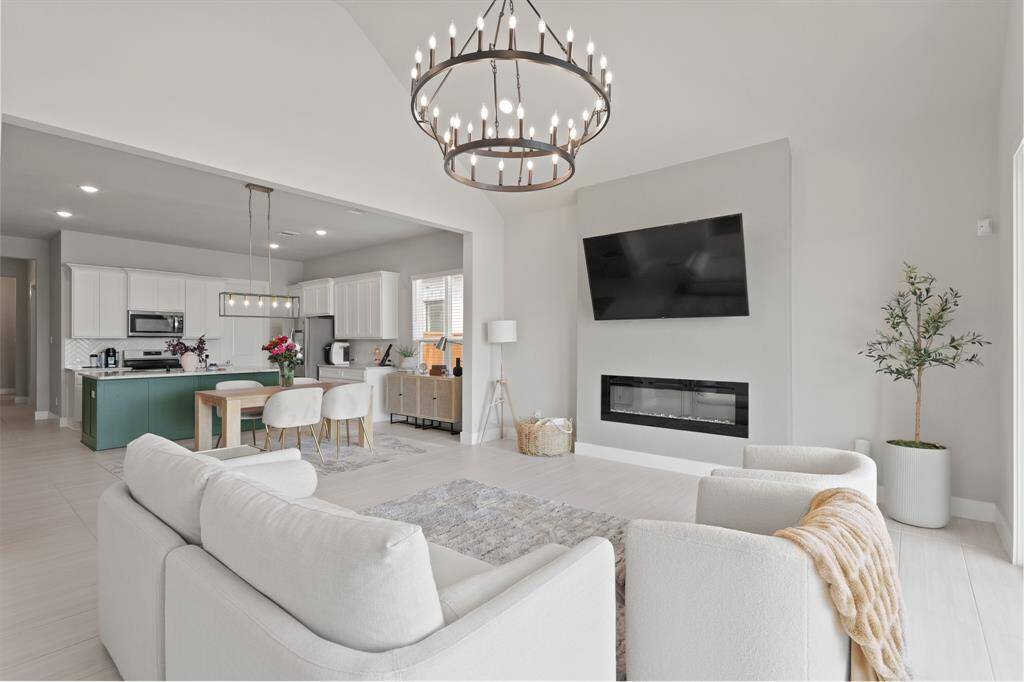 This light-filled living area is the heart of the home, anchored by a sleek modern fireplace and open sightlines to the designer kitchen and elegant dining space.