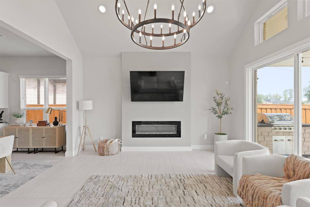 A sleek wall-mounted fireplace adds contemporary charm, while the adjacent living room and backyard access provide both function and flow.