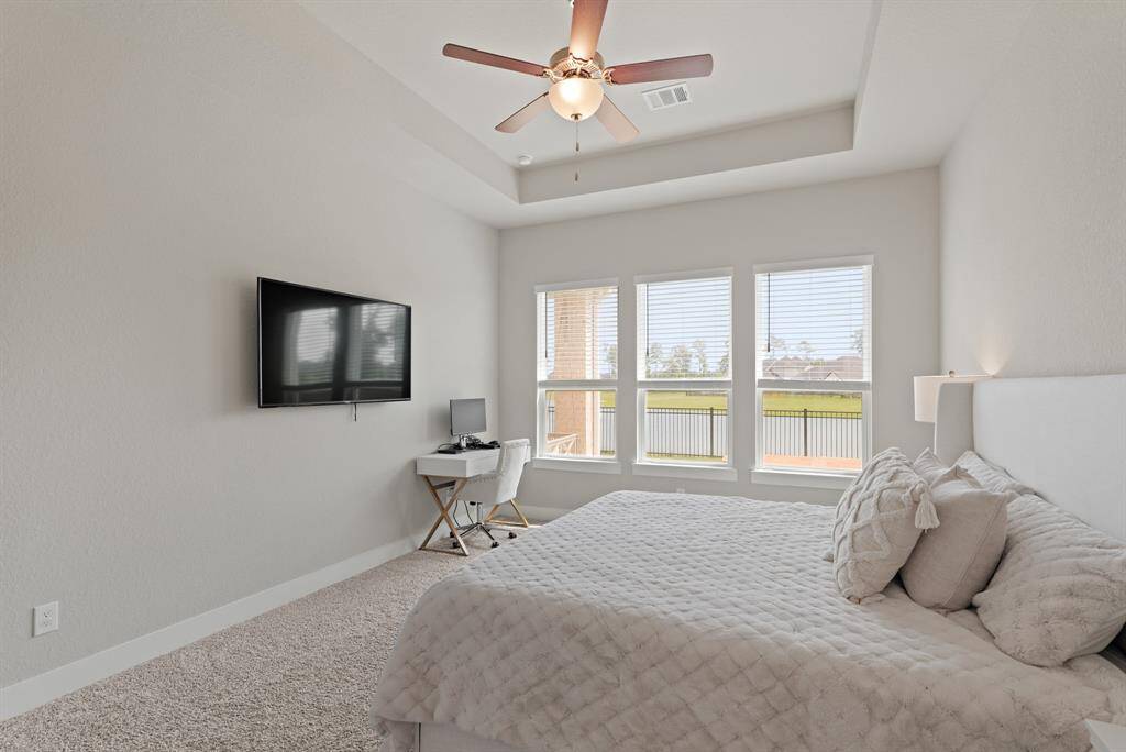 This secondary angle of the primary bedroom highlights the tranquil lake views and cozy layout, featuring a serene reading nook and ample natural light.