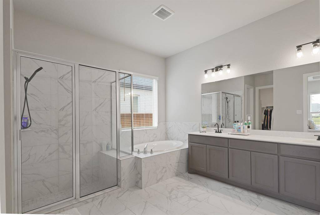The luxurious primary bathroom features a walk-in shower, soaking tub, and expansive dual vanities with abundant counter space and modern lighting.