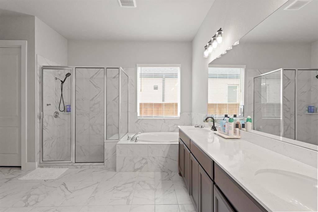 Unwind in the deep soaking tub or refresh in the oversized walk-in shower, all accented by elegant marble-look tile and natural light.
