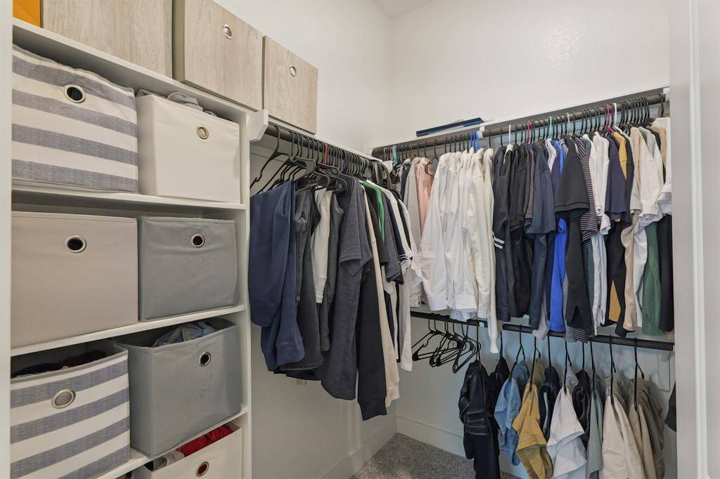 This spacious walk-in closet features double hanging rods and built-in cubby storage, keeping everything organized and within easy reach.