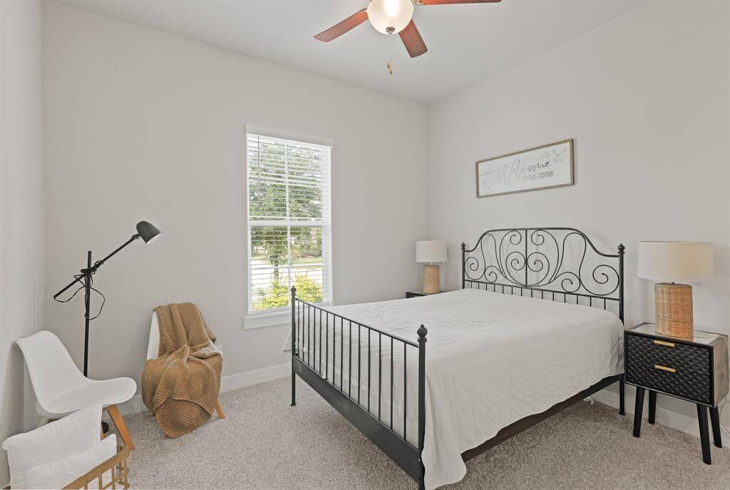 This inviting secondary bedroom offers a cozy atmosphere with plush carpet, natural light, and a peaceful view of the front yard.