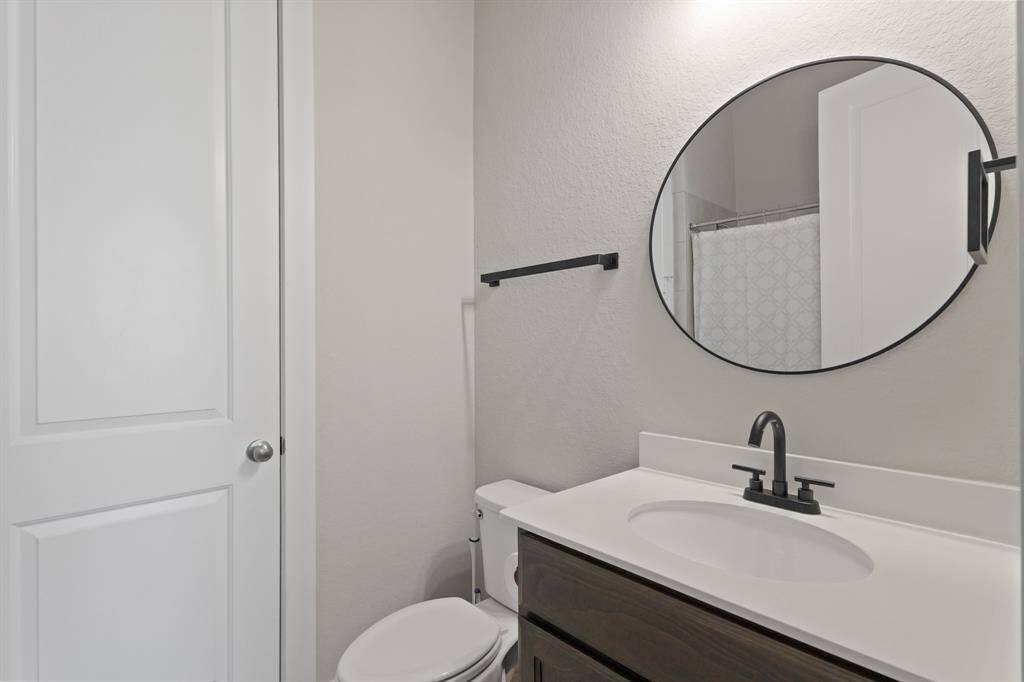 The full guest bathroom features a modern black faucet, round mirror, and sleek fixtures with a combination tub and shower for added functionality.