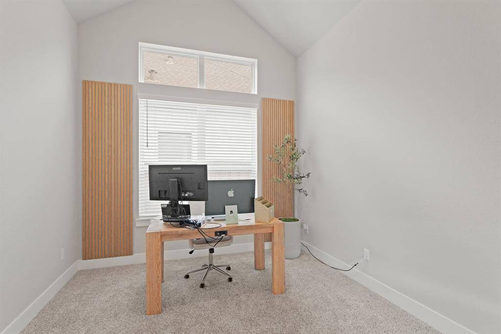 This dedicated home office features soaring ceilings, tall windows for natural light, and plenty of space to create a productive and stylish workspace.