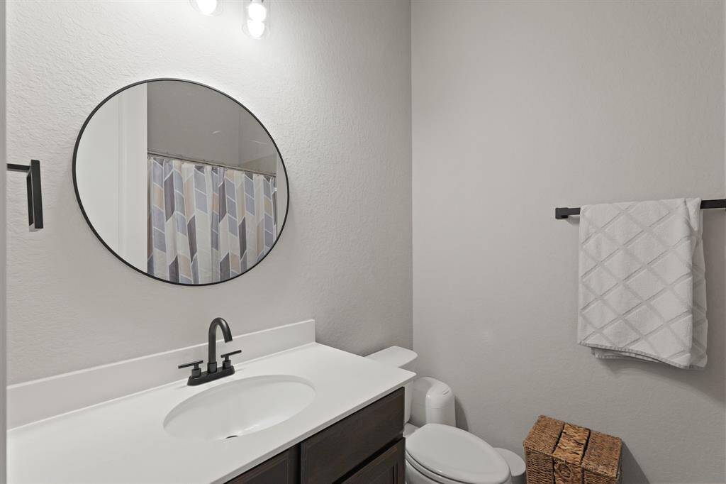 A stylish full bathroom with a modern black faucet, round mirror, and a tub/shower combo—perfect for everyday functionality and comfort.